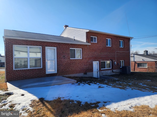 snow covered house with brick siding and central air condition unit