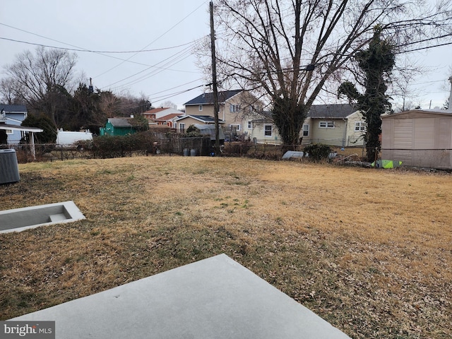 view of yard featuring fence, a residential view, and central air condition unit