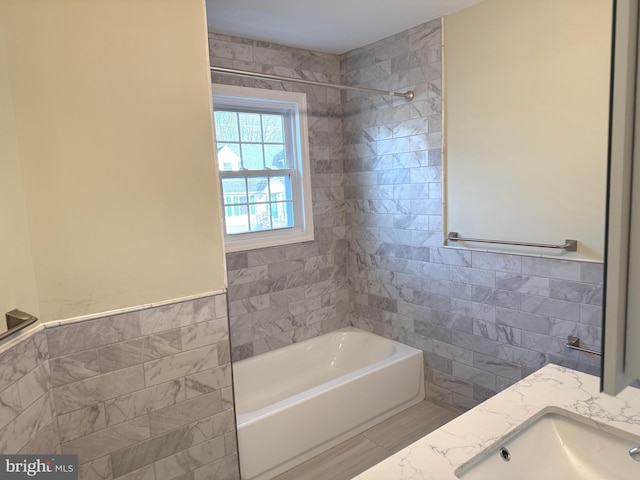 bathroom with tiled shower / bath, vanity, and tile walls