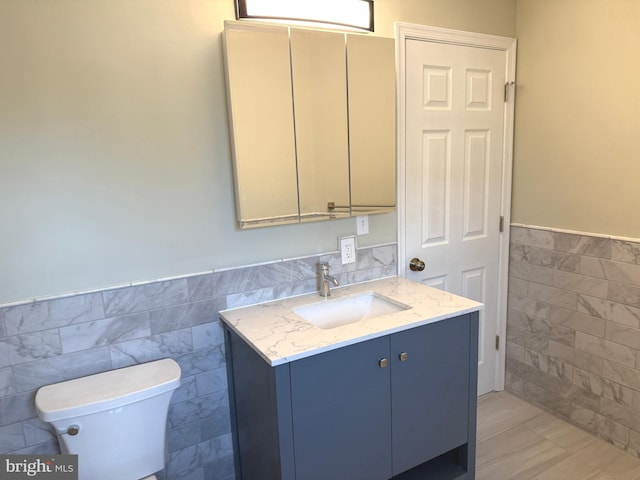 bathroom featuring tile walls, vanity, and toilet