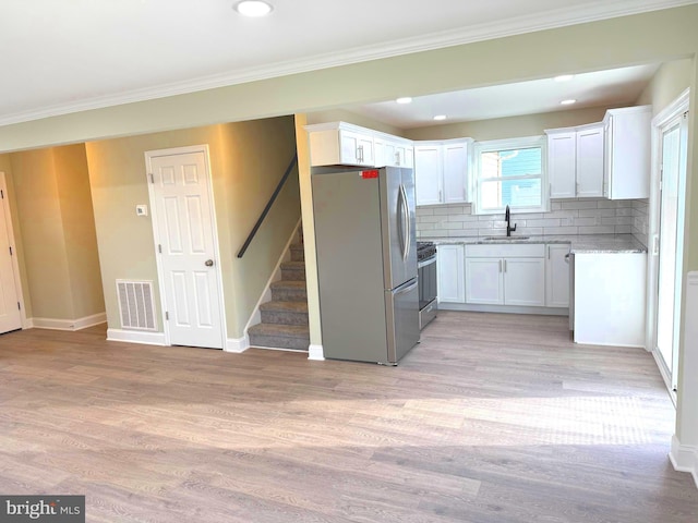 kitchen featuring white cabinetry, sink, light hardwood / wood-style flooring, and appliances with stainless steel finishes