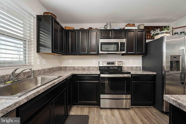 kitchen with sink, stainless steel appliances, and light hardwood / wood-style floors