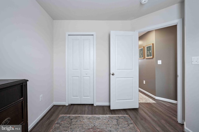 unfurnished bedroom with a closet and dark hardwood / wood-style flooring