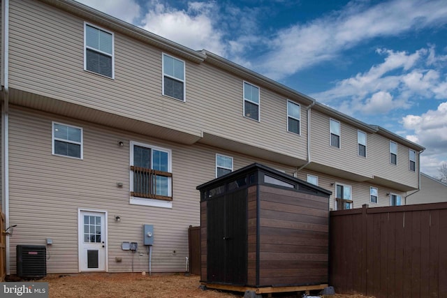 back of house with central air condition unit and a shed