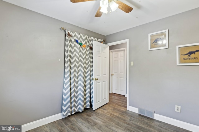 unfurnished bedroom featuring dark wood-type flooring and ceiling fan