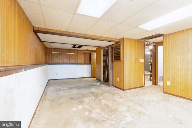 basement with wooden walls and a paneled ceiling