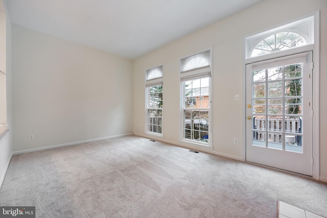 spare room featuring a healthy amount of sunlight, light carpet, and visible vents