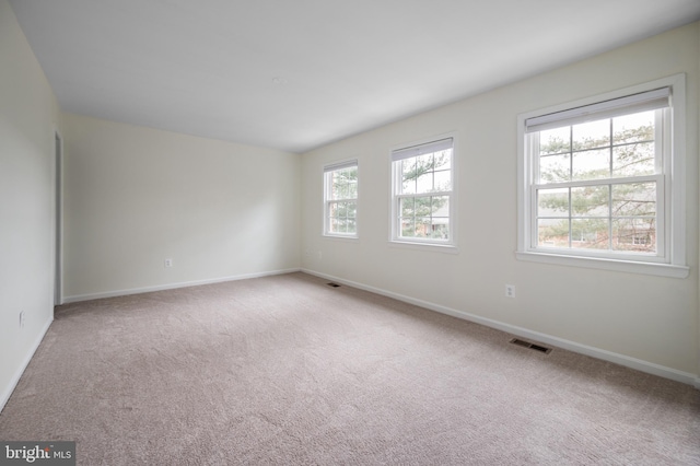 empty room featuring carpet, visible vents, and baseboards