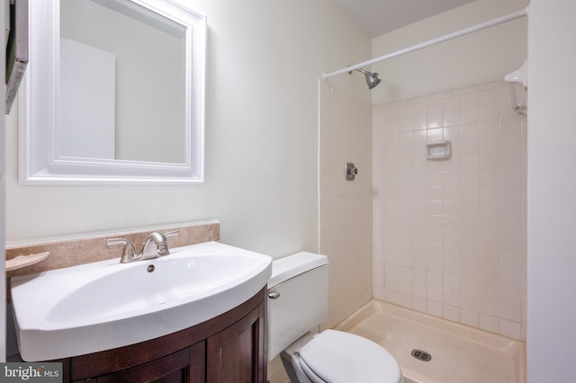 full bath featuring tiled shower, vanity, and toilet