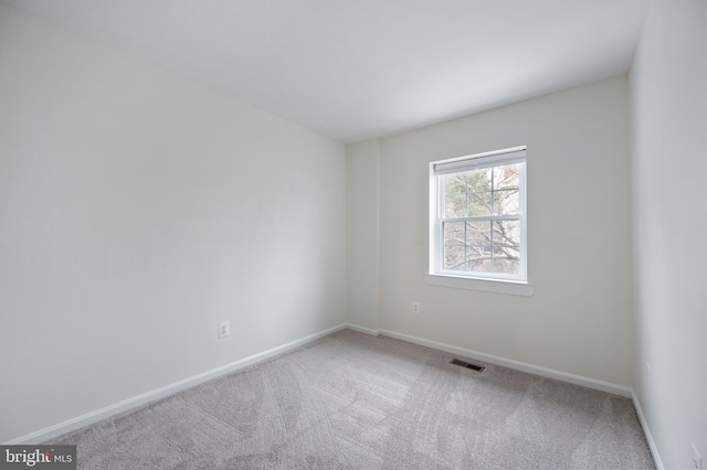 carpeted spare room with visible vents and baseboards