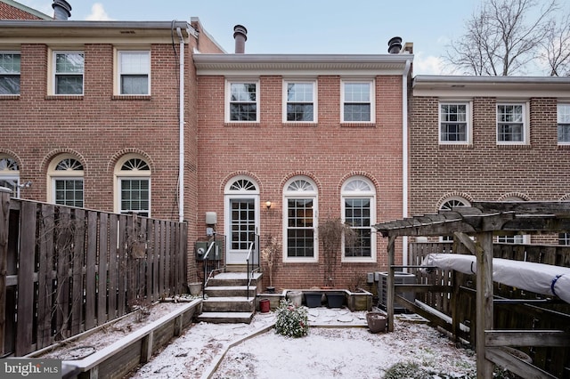 snow covered house with brick siding and fence