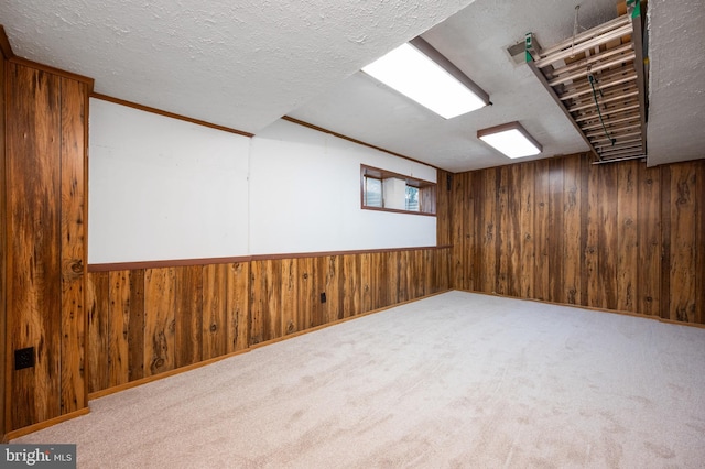 below grade area featuring light carpet, wood walls, and a textured ceiling