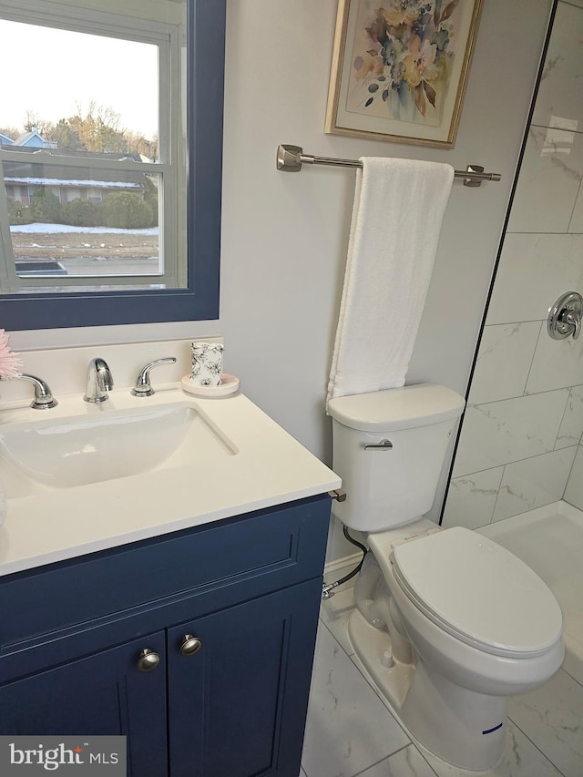 bathroom with vanity, a tile shower, and toilet