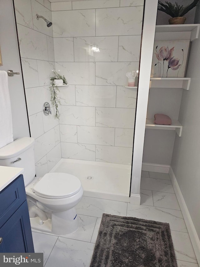 bathroom with vanity, tiled shower, and toilet