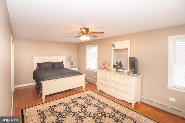 bedroom with hardwood / wood-style flooring, a baseboard radiator, and ceiling fan