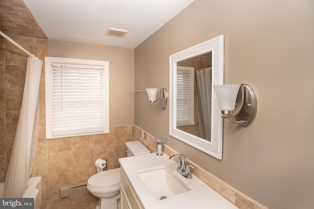 full bathroom featuring toilet, tile walls, baseboard heating, vanity, and shower / bath combo