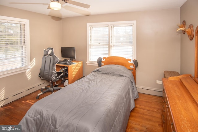 bedroom featuring wood-type flooring, a baseboard heating unit, and ceiling fan