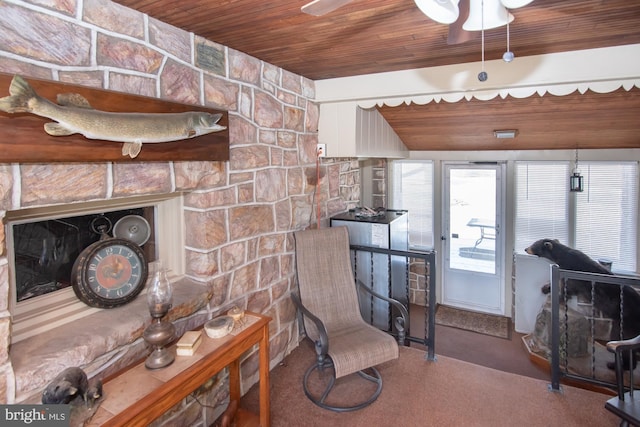 interior space with ceiling fan, a stone fireplace, and wood ceiling