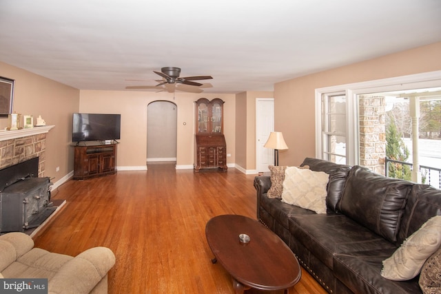 living room with hardwood / wood-style flooring, ceiling fan, and a fireplace