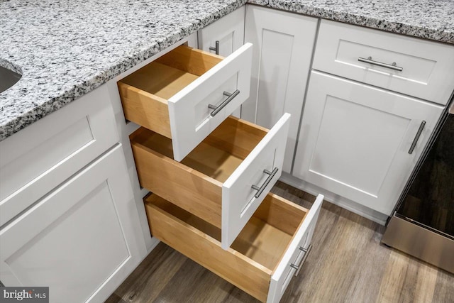 details featuring white cabinetry, hardwood / wood-style floors, and light stone countertops