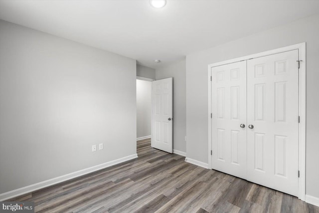 unfurnished bedroom with dark hardwood / wood-style floors and a closet