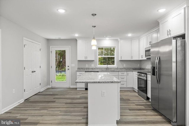 kitchen with stainless steel appliances, white cabinetry, a kitchen island, and pendant lighting