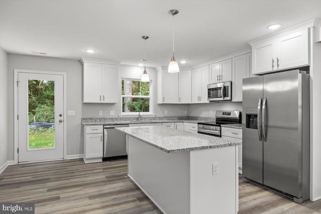 kitchen featuring white cabinetry, light stone counters, decorative light fixtures, a center island, and appliances with stainless steel finishes