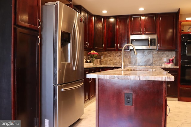 kitchen featuring a kitchen island with sink, sink, decorative backsplash, and appliances with stainless steel finishes