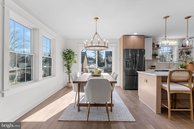 dining room featuring sink, an inviting chandelier, and light hardwood / wood-style flooring