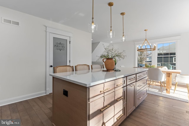 kitchen featuring a kitchen island, dark hardwood / wood-style floors, pendant lighting, a breakfast bar area, and a chandelier