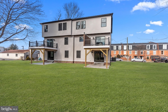 rear view of property featuring a yard, a deck, and a patio