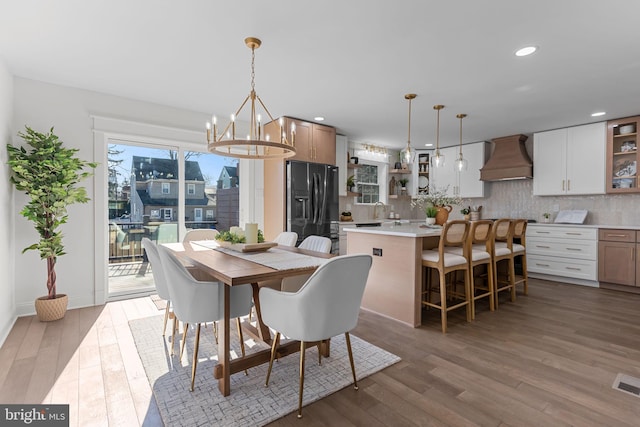 dining area with an inviting chandelier, sink, and light hardwood / wood-style floors