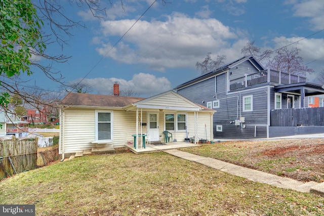 rear view of property featuring a balcony and a yard