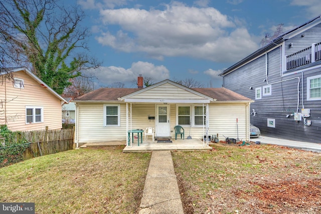 rear view of house with a lawn and a porch