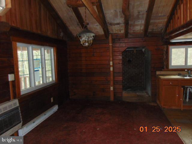 interior space with wooden walls, vaulted ceiling with beams, sink, a baseboard heating unit, and wooden ceiling