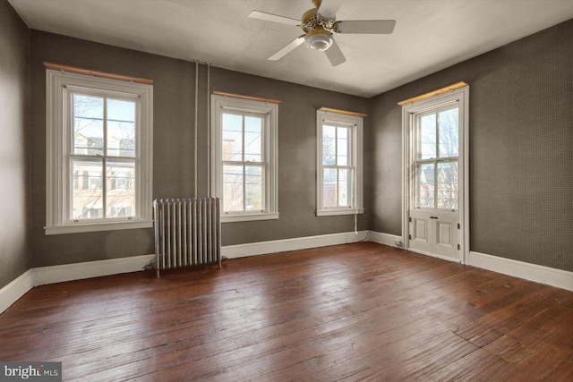 empty room featuring ceiling fan, dark hardwood / wood-style flooring, and radiator