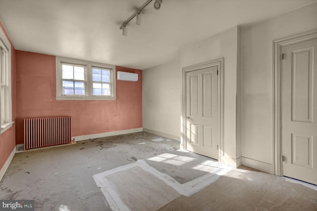 spare room with radiator, a wall mounted air conditioner, and track lighting