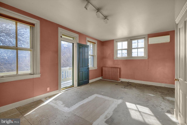 unfurnished room featuring rail lighting, radiator, and a wall unit AC