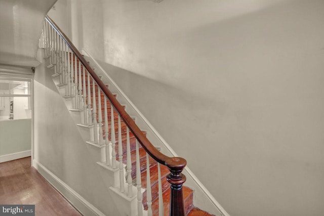 staircase featuring a high ceiling and hardwood / wood-style floors