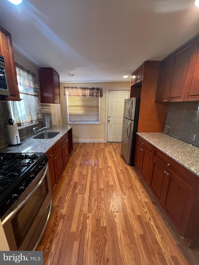 kitchen featuring light stone counters, appliances with stainless steel finishes, sink, and wood-type flooring