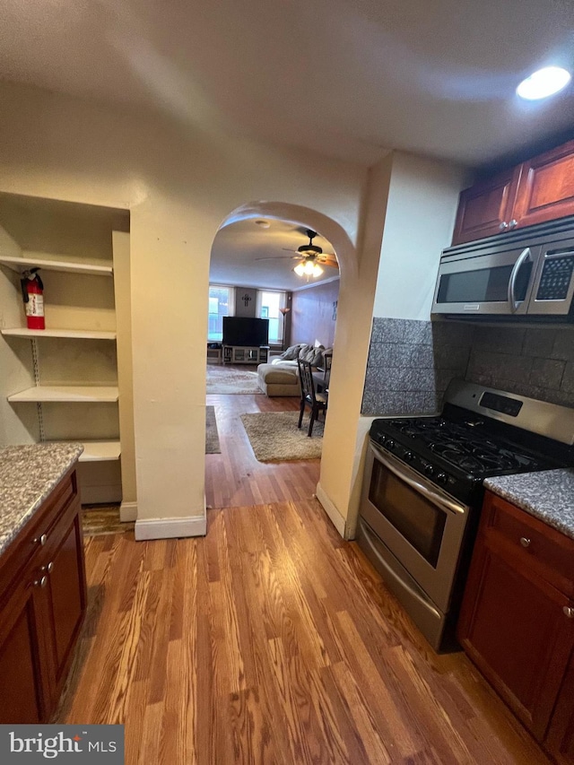 kitchen with wood-type flooring, appliances with stainless steel finishes, and light stone counters