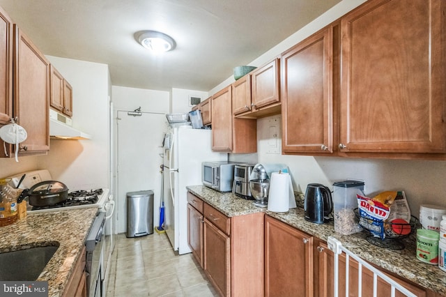 kitchen featuring light stone counters, white appliances, and light tile patterned flooring