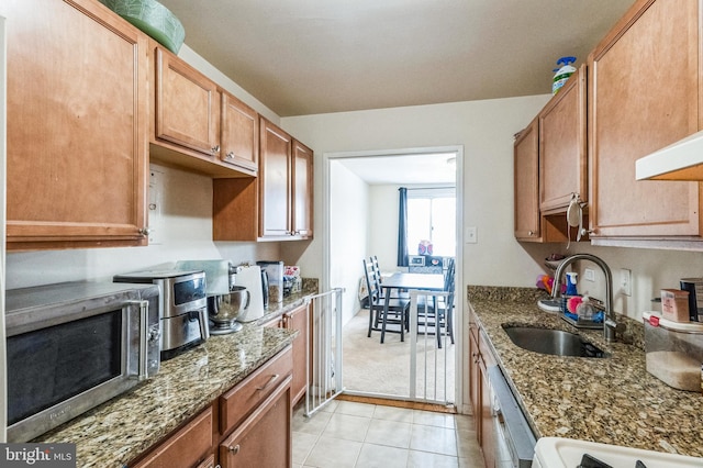 kitchen featuring stone counters, sink, dishwashing machine, range, and light tile patterned floors