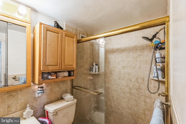 bathroom with toilet, tile walls, and a shower with shower door