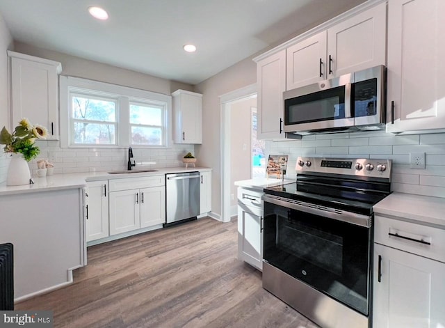 kitchen featuring sink, tasteful backsplash, light hardwood / wood-style flooring, stainless steel appliances, and white cabinets