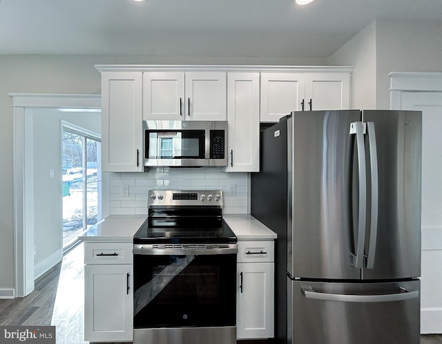 kitchen featuring backsplash, appliances with stainless steel finishes, hardwood / wood-style flooring, and white cabinets