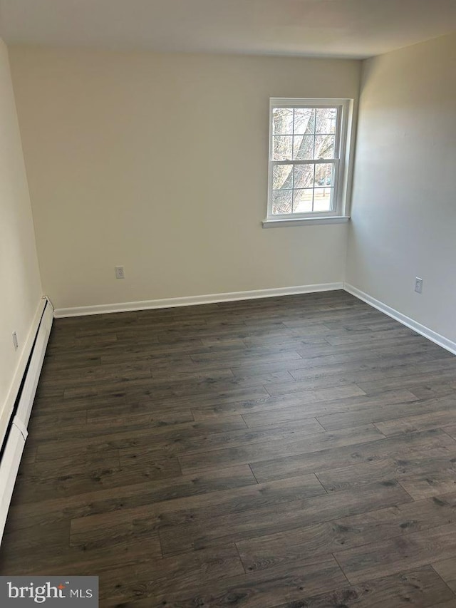 empty room featuring dark wood-type flooring and a baseboard radiator