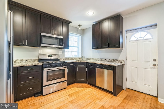 kitchen featuring appliances with stainless steel finishes, dark brown cabinets, and light hardwood / wood-style floors