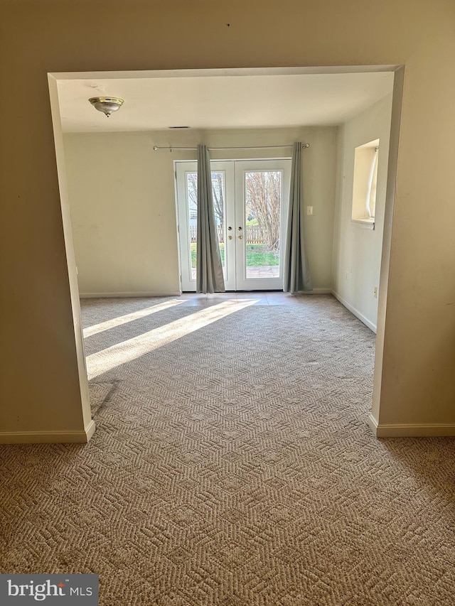 empty room featuring french doors, baseboards, and carpet