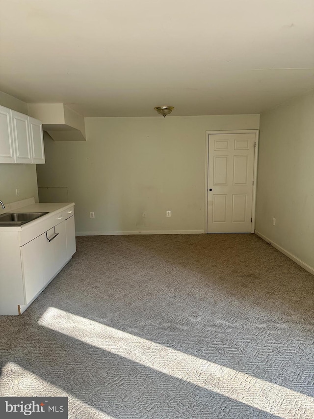 spare room with light colored carpet, baseboards, and a sink